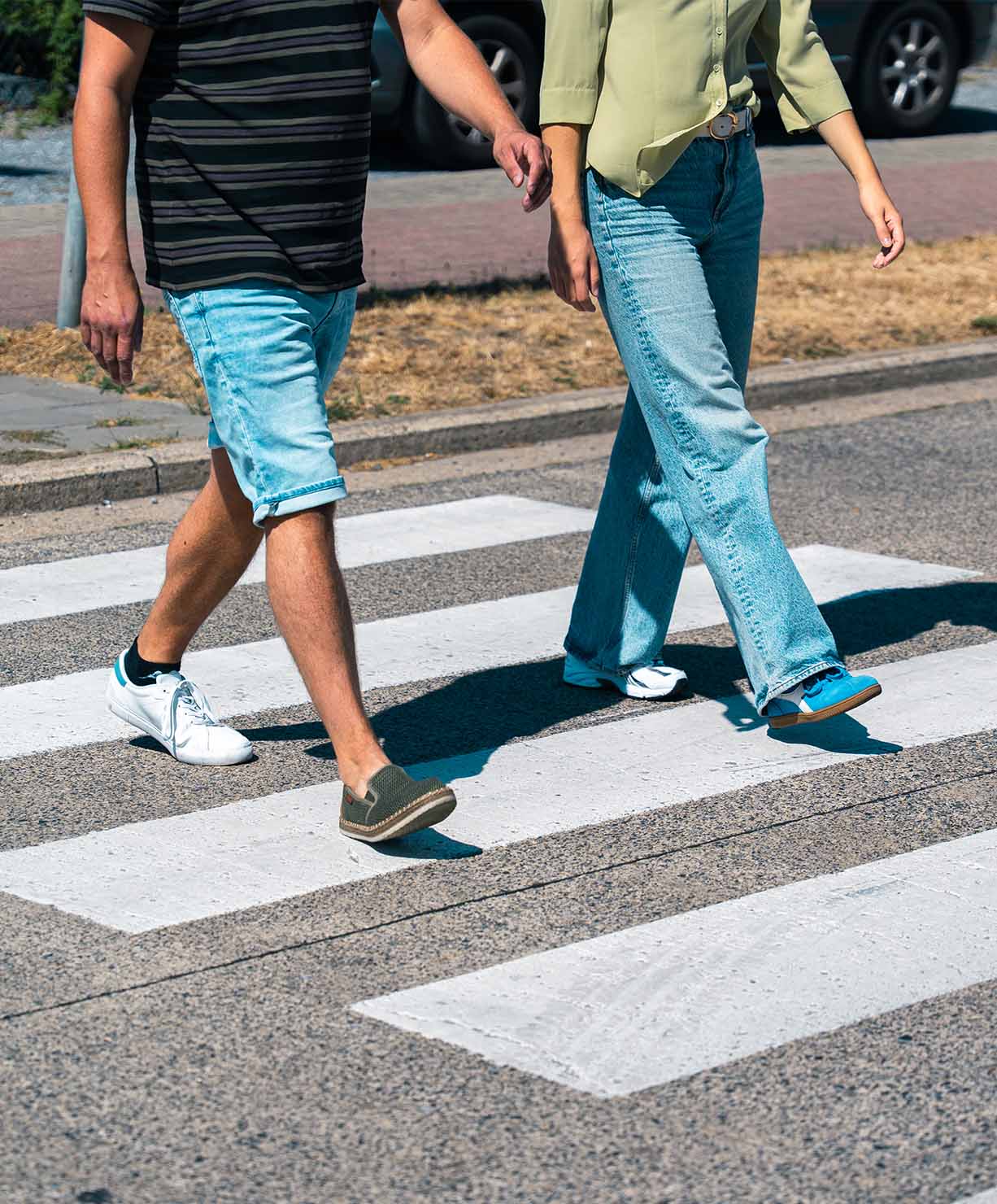 Two persones crossing the street wearing two different shoes